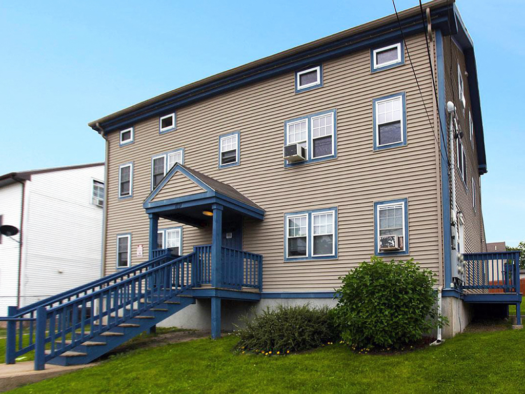 a brown house with stairs and a blue balcony