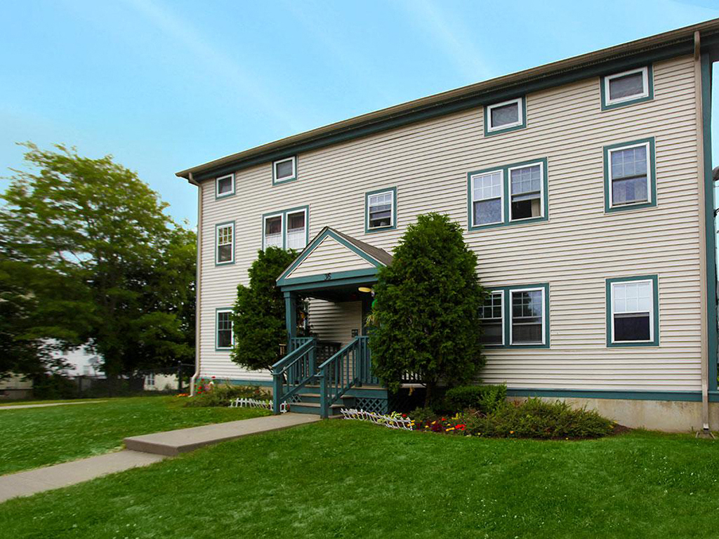 a yellow house with a porch and a green lawn
