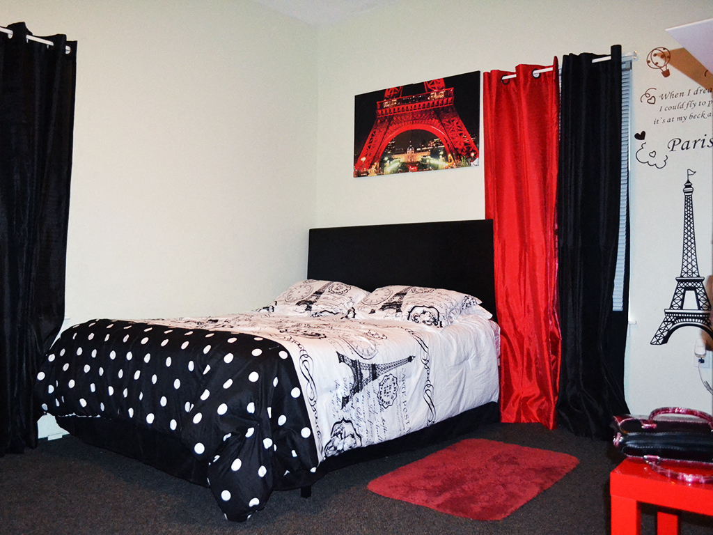 a bedroom with a black and white bed and red curtains