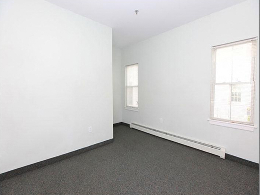 an empty room with carpet and two windows