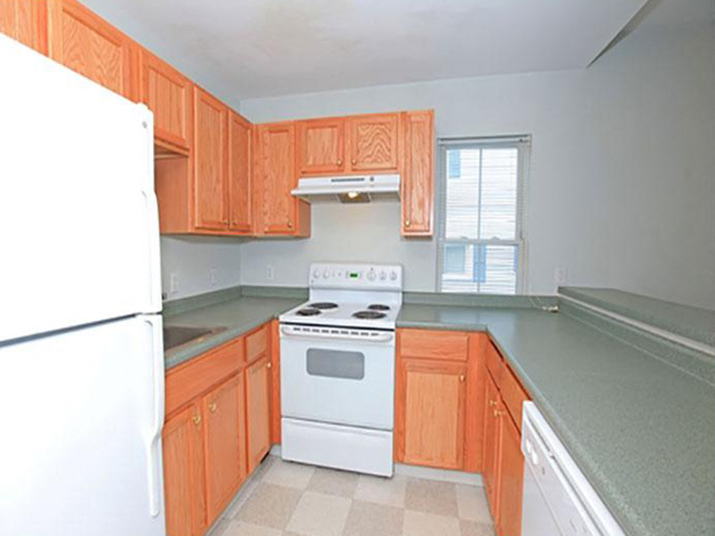 a kitchen with wooden cabinets and a white stove and refrigerator