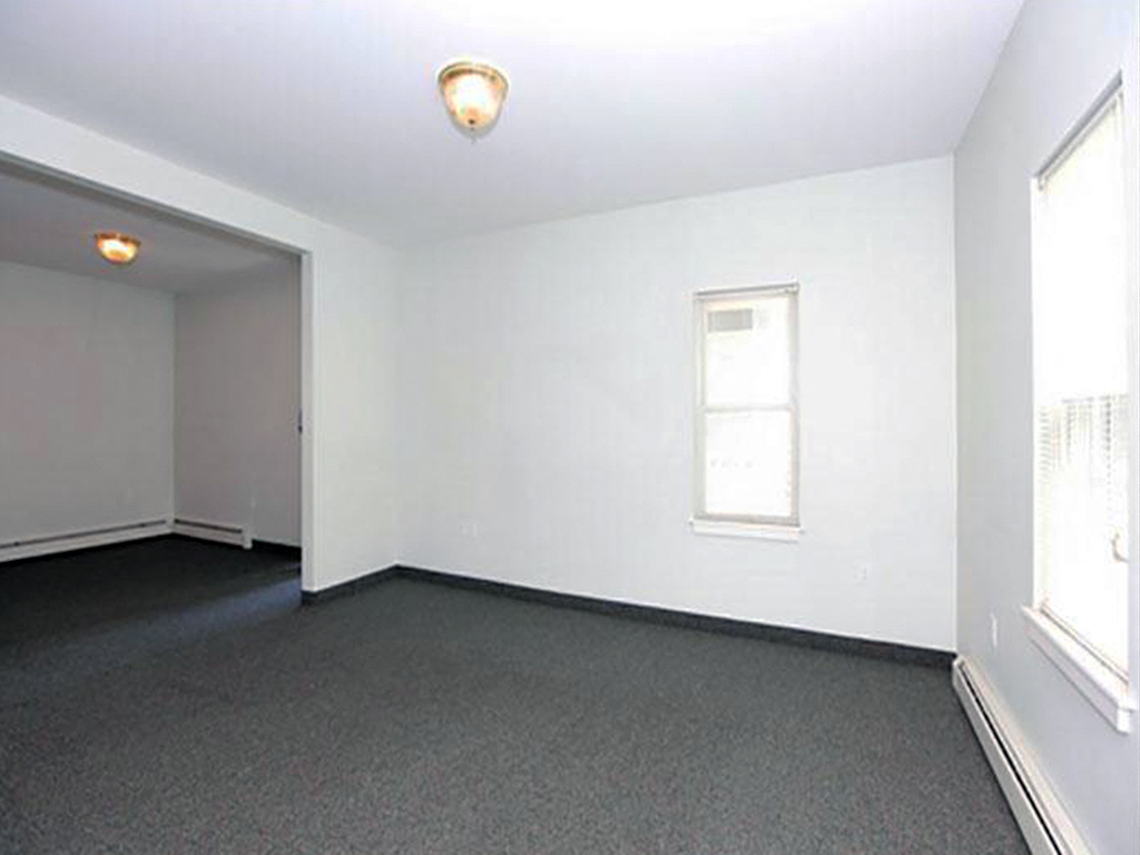 an empty living room with white walls and a window