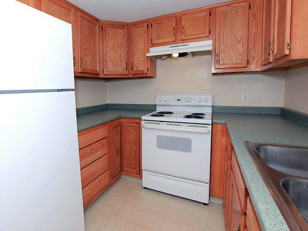 a kitchen with wooden cabinets and a white stove and refrigerator