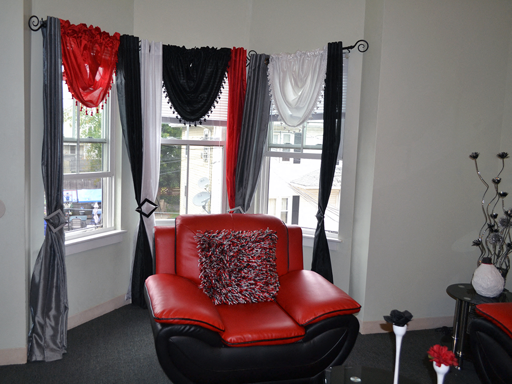 a red leather chair in front of windows with black and red curtains