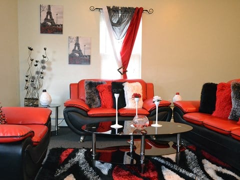 a living room with red furniture and a black and white rug