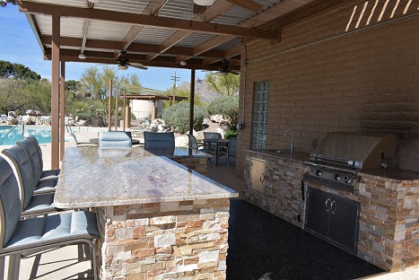 a patio with a bar and a grill and a pool