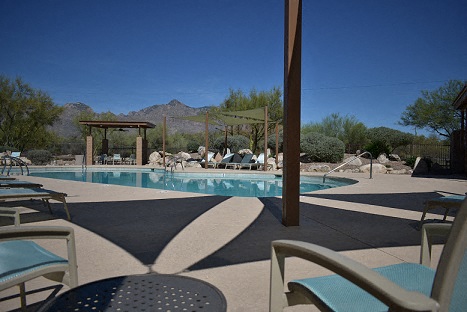a swimming pool with chairs and tables around it