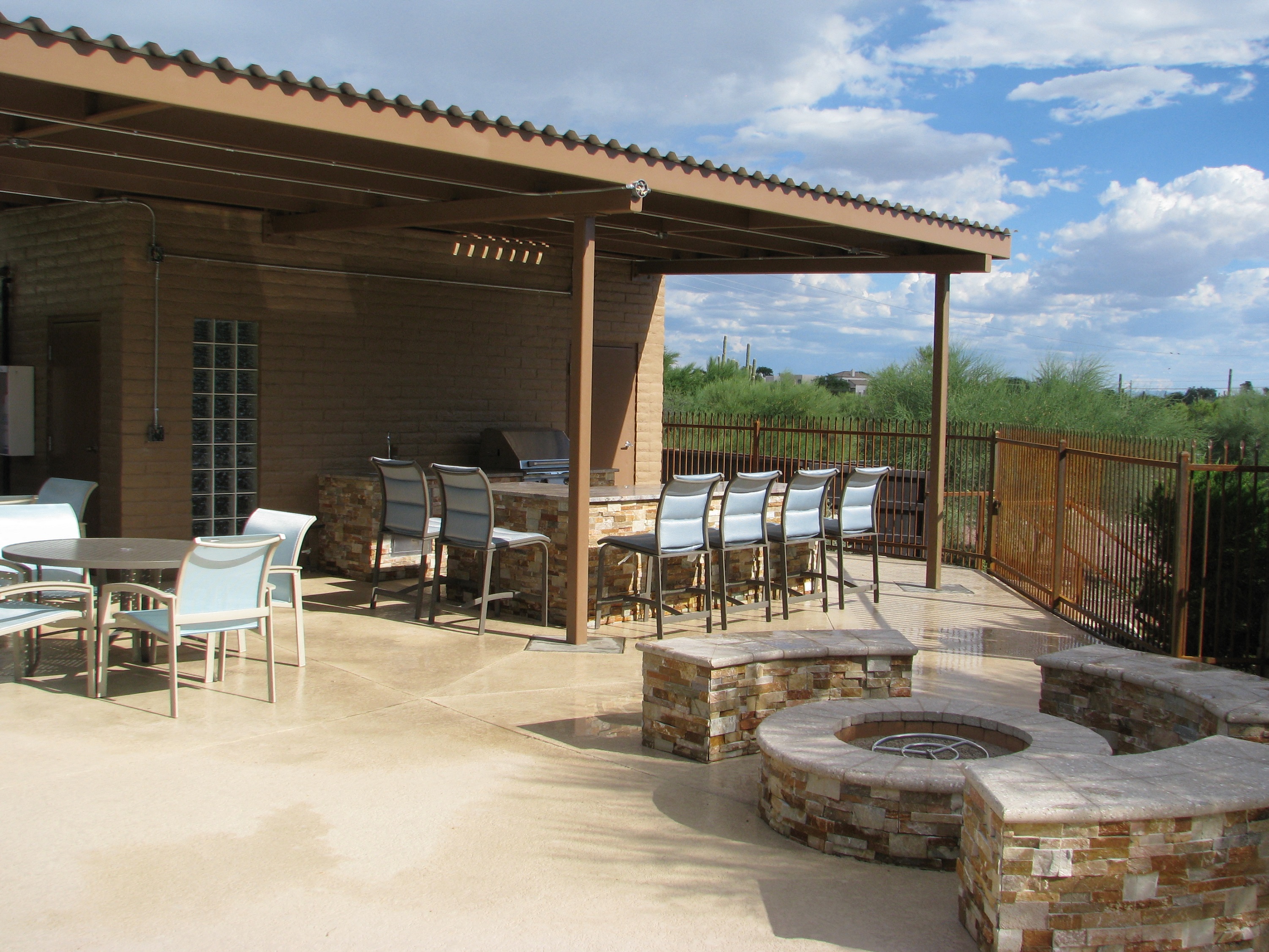 a covered patio with a fire pit and tables
