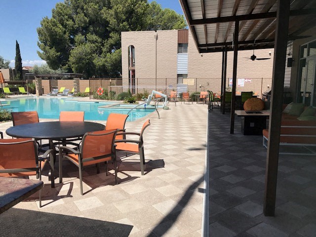 a swimming pool with a patio with tables and chairs