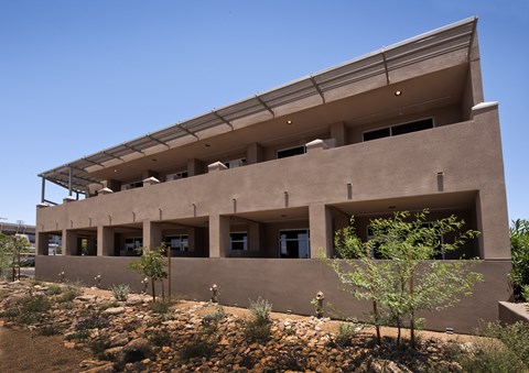 an image of the back of a building with trees and bushes
