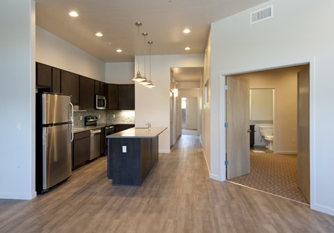 a kitchen with stainless steel appliances and a long hallway with a door to a bathroom