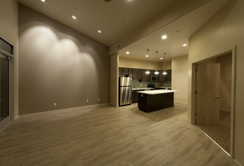 an empty living room and kitchen with a refrigerator and a sink