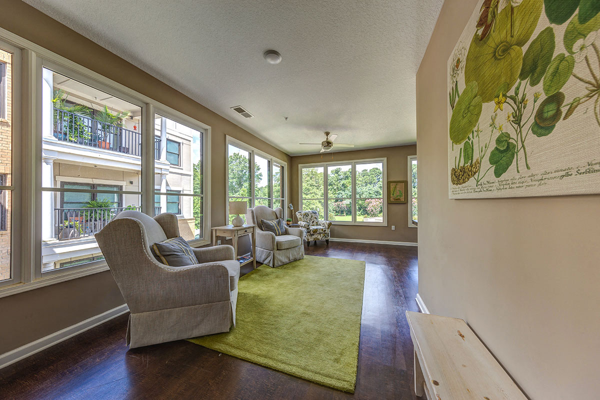 a living room with couches and chairs and large windows
