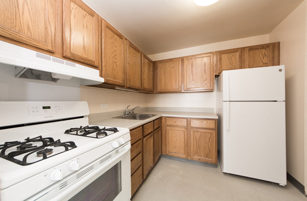 an empty kitchen with white appliances and wooden cabinets