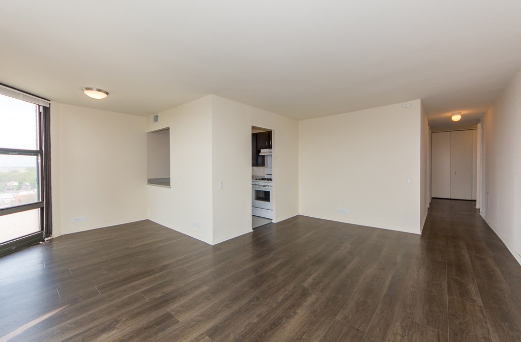 an empty living room with wood flooring and a window