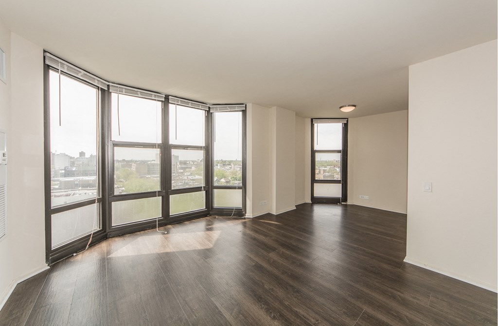 an empty living room with wood floors and large windows