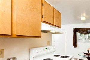 Village on Cowan interior features a kitchen with wood cabinets and white appliances.