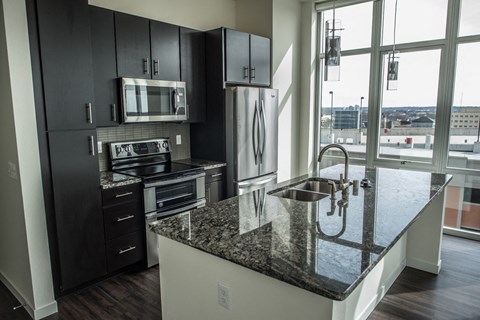 A kitchen with black cabinets and granite countertops.