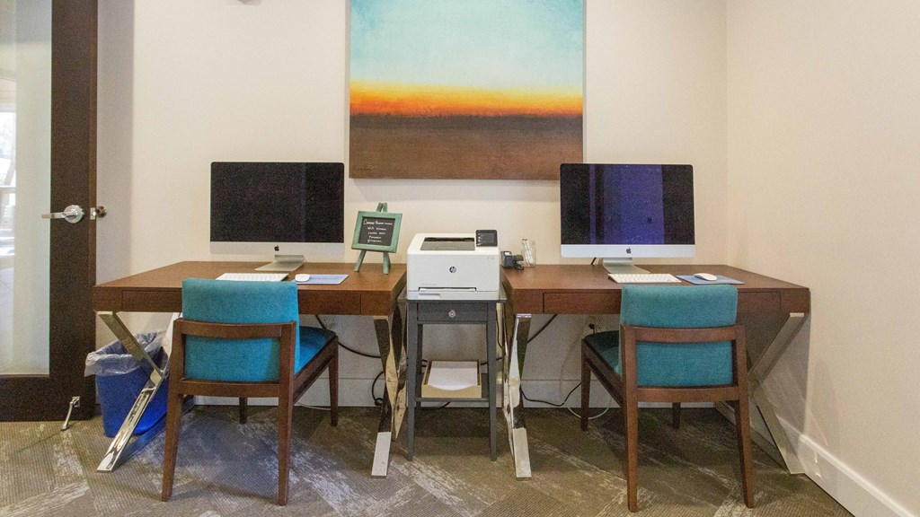 a computer desk with two monitors and three chairs