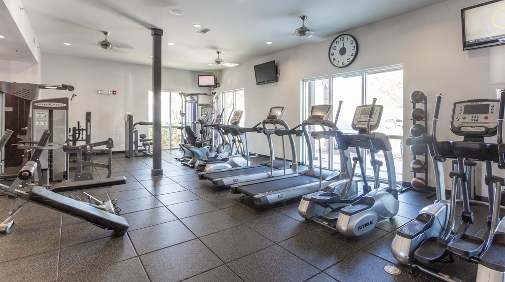 a gym with cardio equipment and a large window