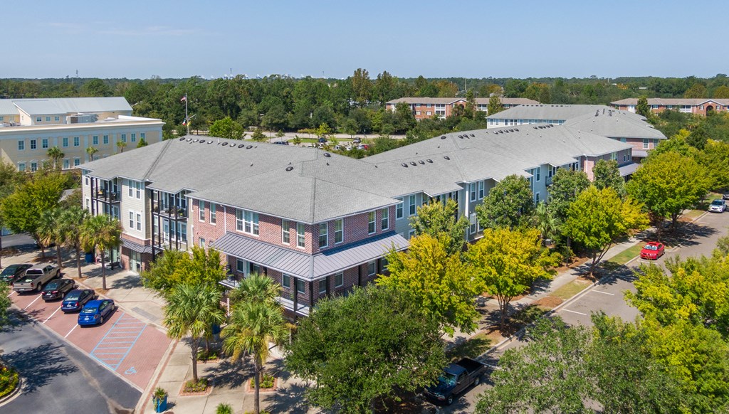 an aerial view of a building with a parking lot and trees