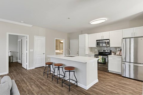 A kitchen with white cabinets and a white island with brown stools.