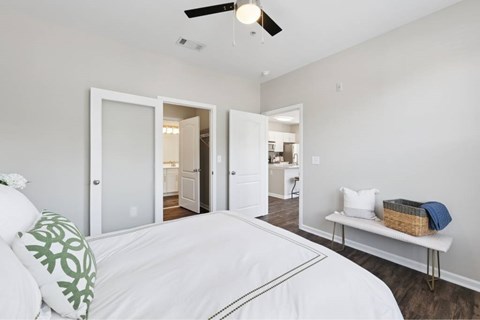 A bedroom with a white bed and a ceiling fan.