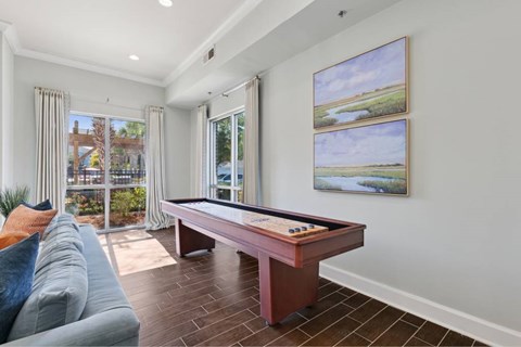 A pool table in a room with a view of a tree-lined landscape.