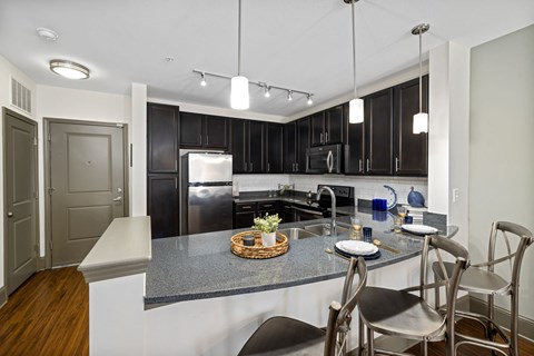 a kitchen with black cabinets and a marble counter top