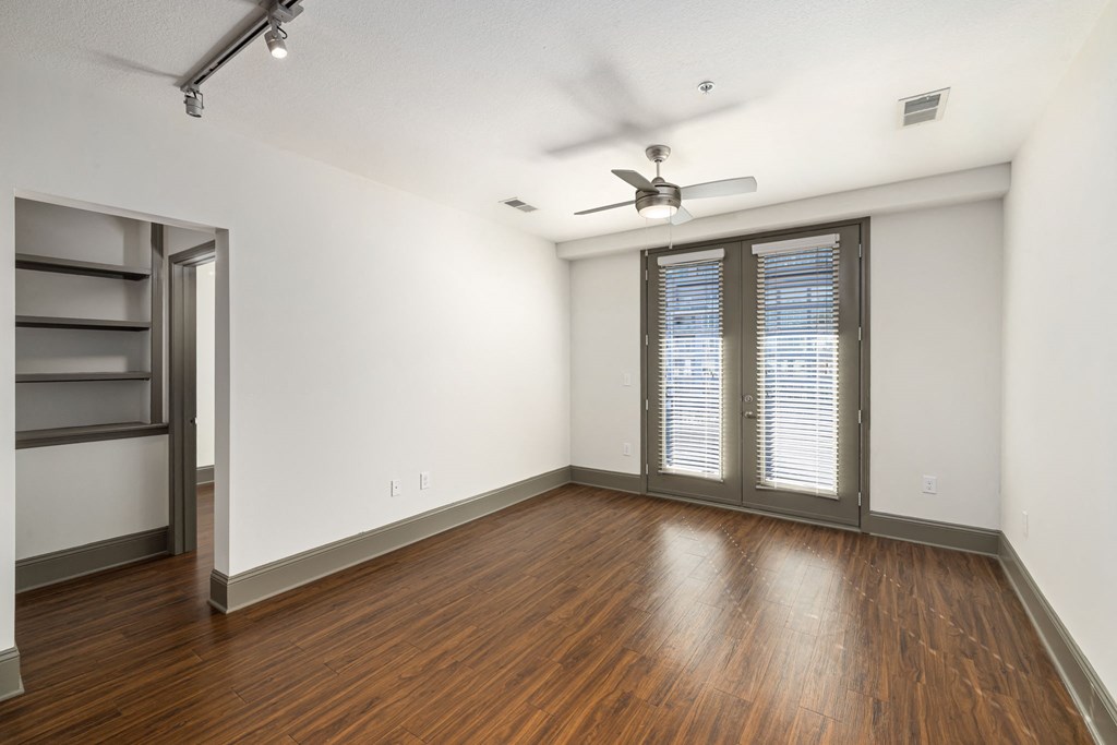 an empty living room with wood floors and a ceiling fan