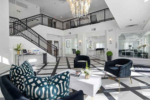 a living room with black and white checkered floors and a staircase