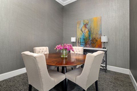 a dining room with a table and chairs and a painting on the wall