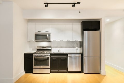 a modern kitchen with stainless steel appliances and white cabinets