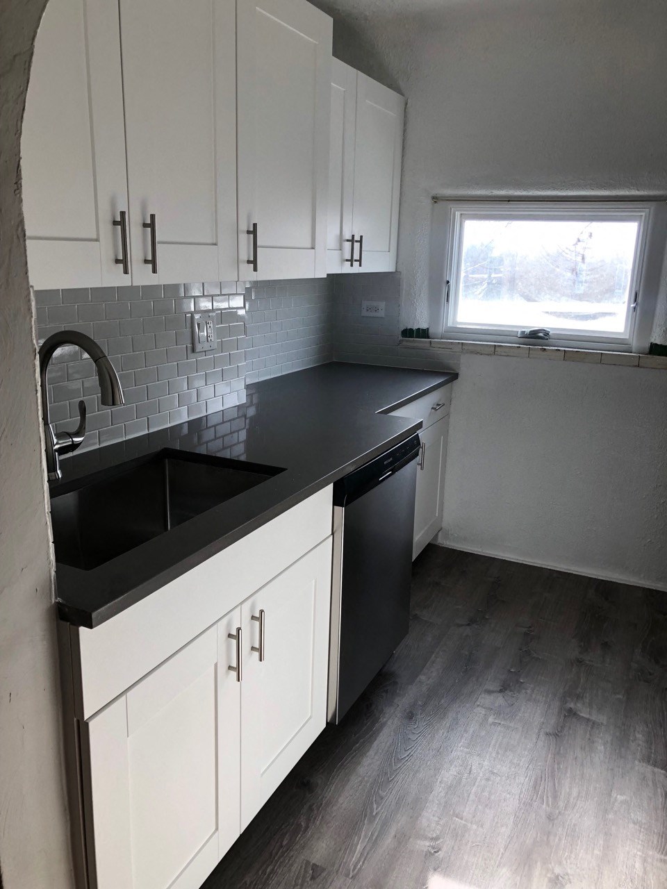 a new kitchen with white cabinets and a black counter top