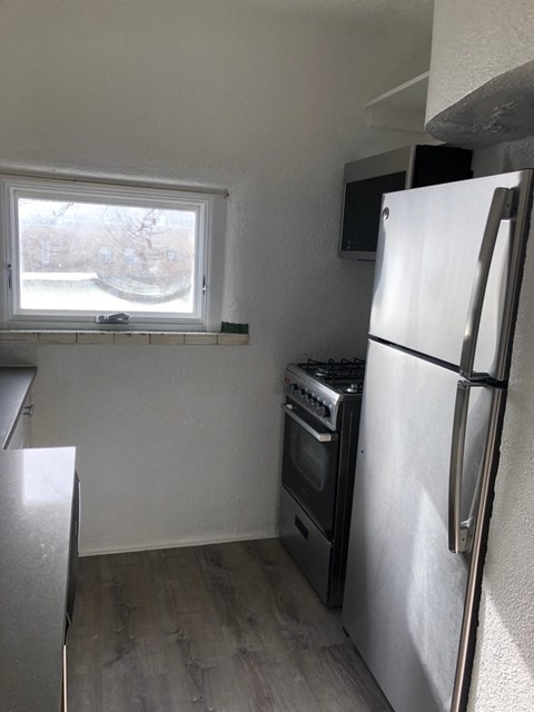 an empty kitchen with a refrigerator and a window