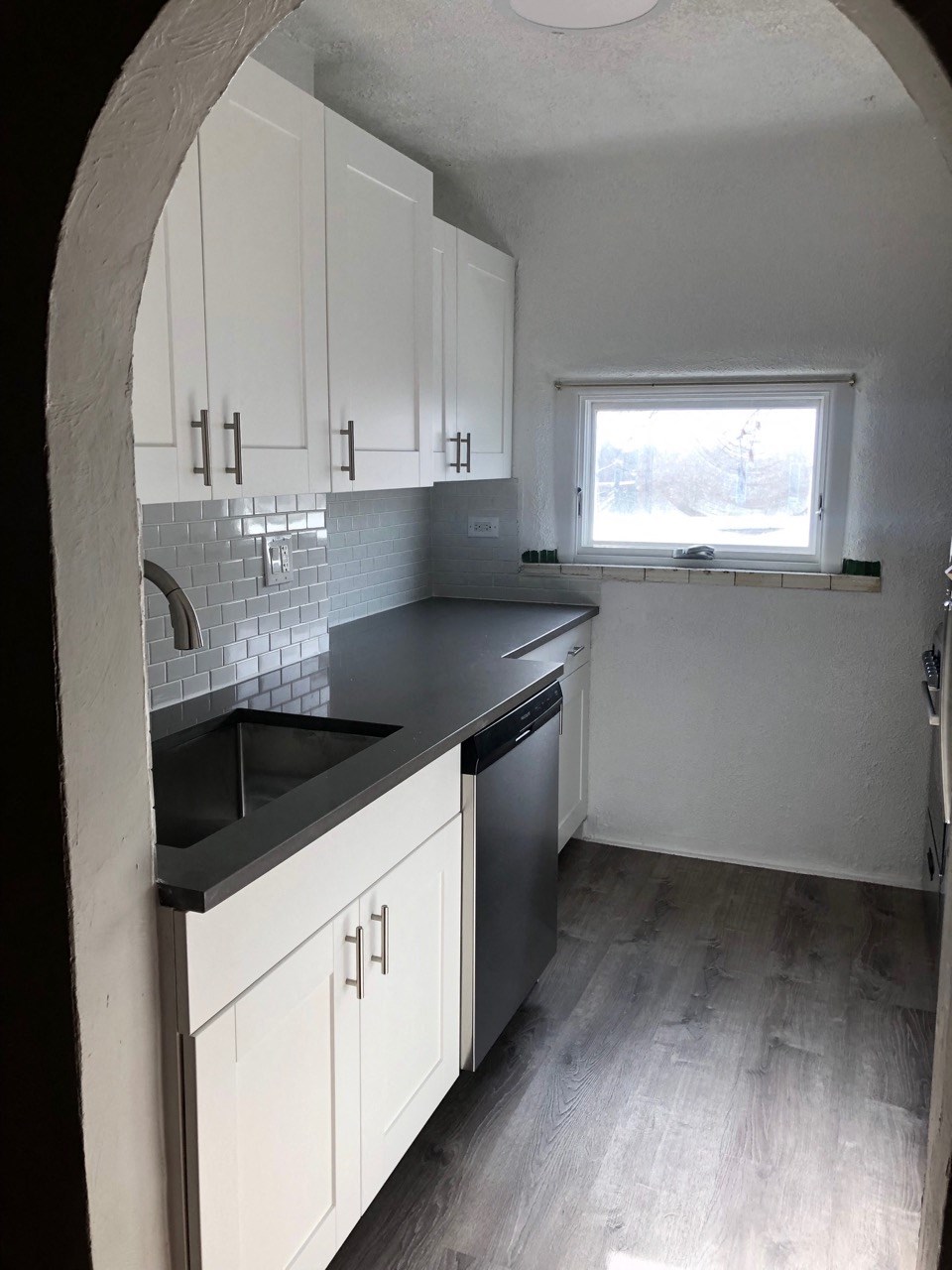 an empty kitchen with white cabinets and a black counter top