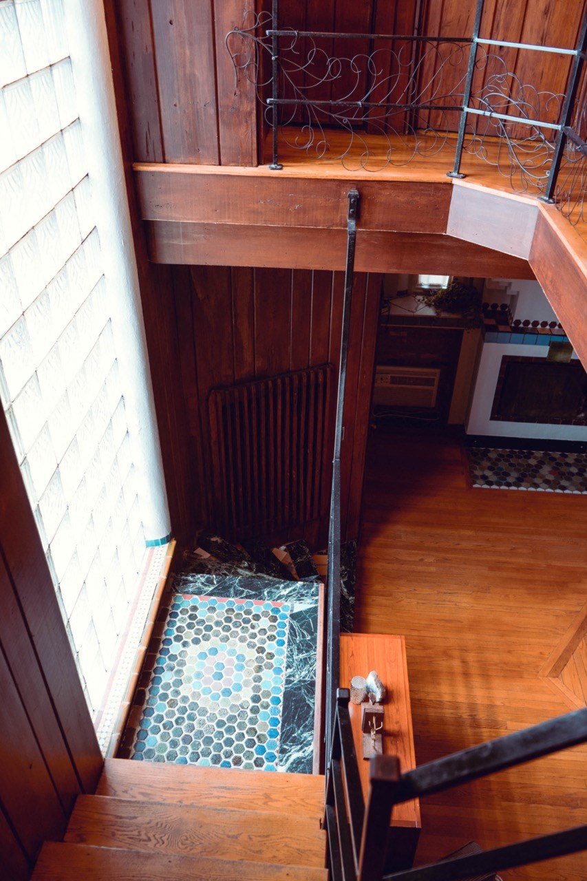 a view from the top of the stairs looking down at a tiled floor