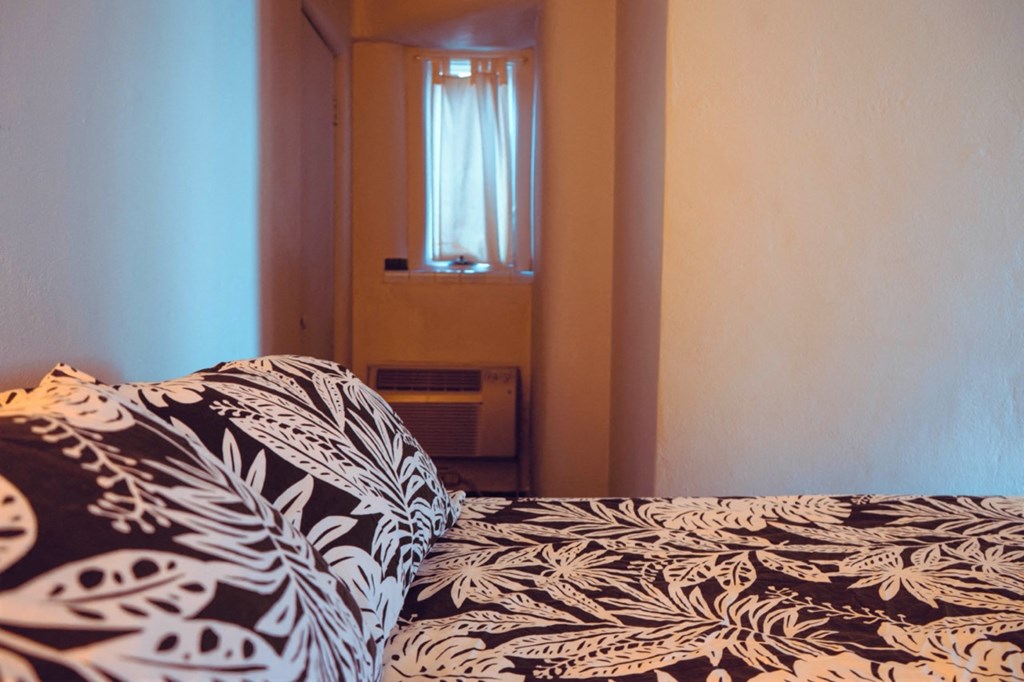 a bed with a black and white comforter in a room with a window