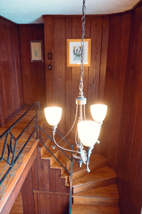 the chandelier hanging above the stairs in a wood paneled room