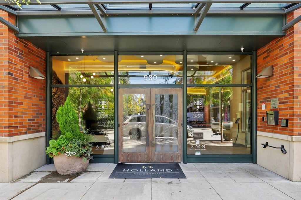 the front of a store with glass doors and a sign on the sidewalk