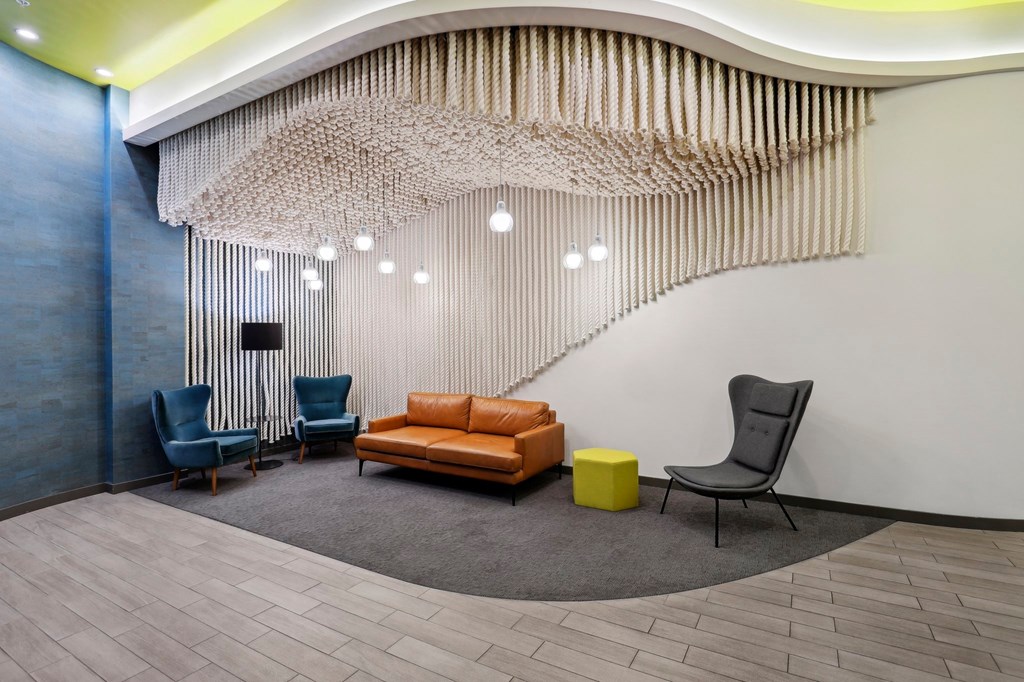 a lobby with a couch and chairs and a wall with a staircase