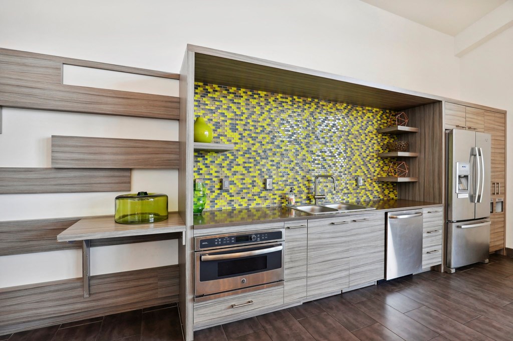a kitchen with a yellow and white tile backsplash and stainless steel appliances