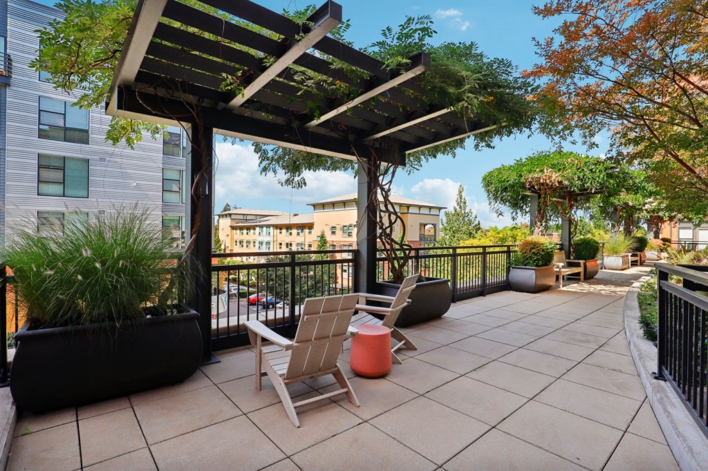 a patio with chairs and a pergola on a balcony