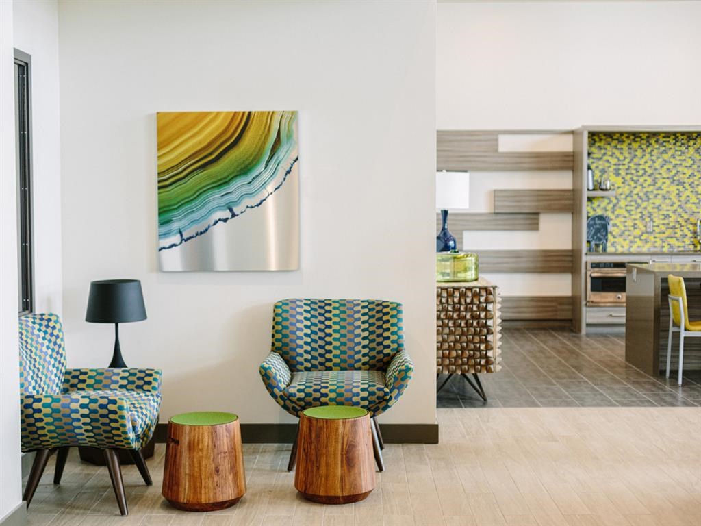 a living room with chairs and a painting on the wall