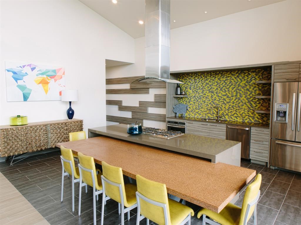 a kitchen with a large island and yellow chairs