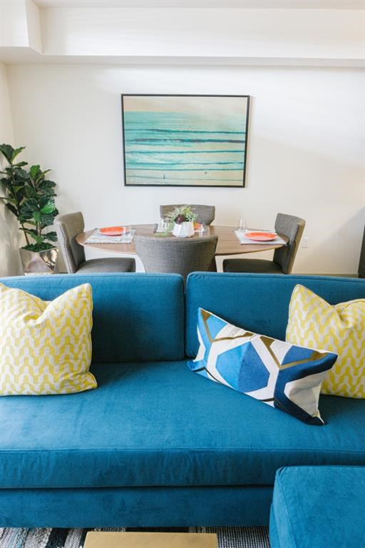 a living room with a blue couch and yellow and white pillows