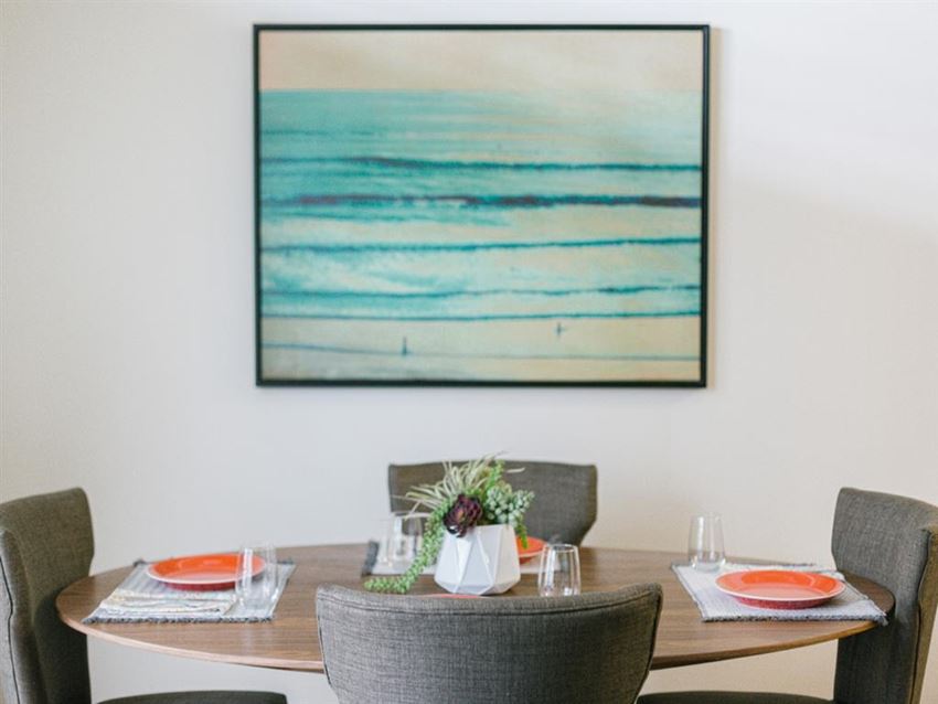 a dining room with a table and a painting of the ocean