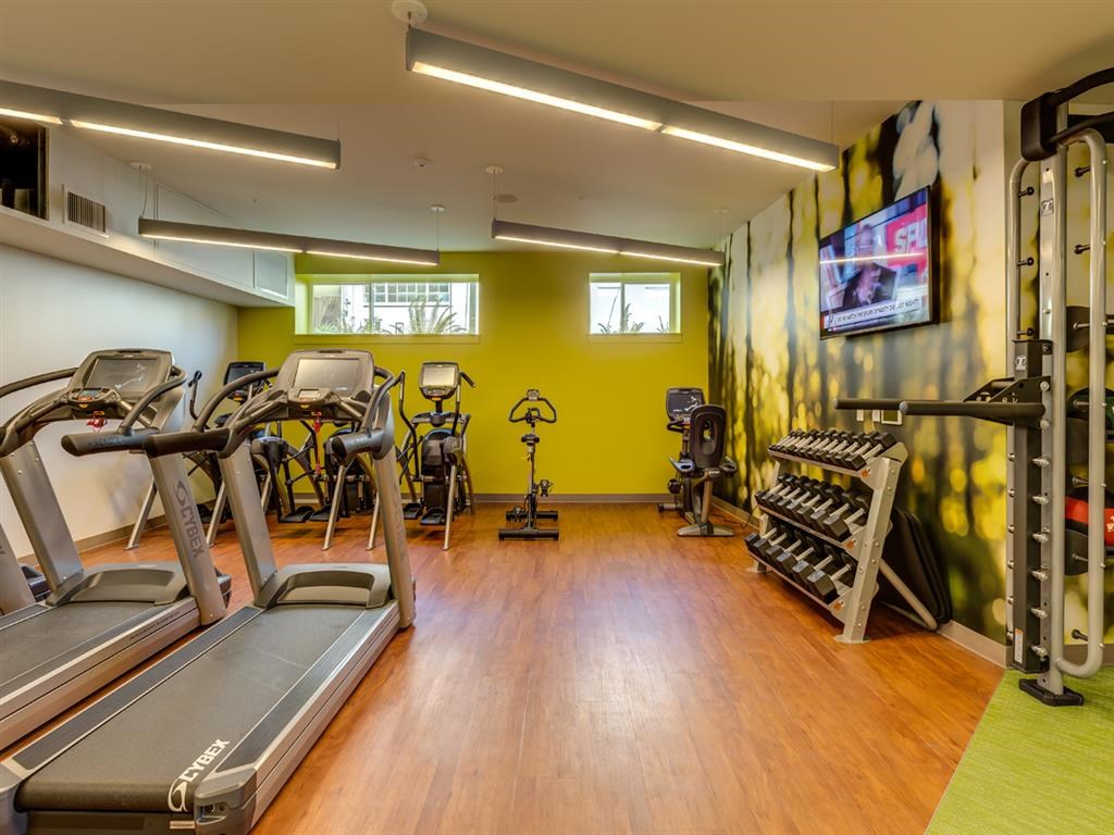 a gym with cardio equipment and weights on a wooden floor