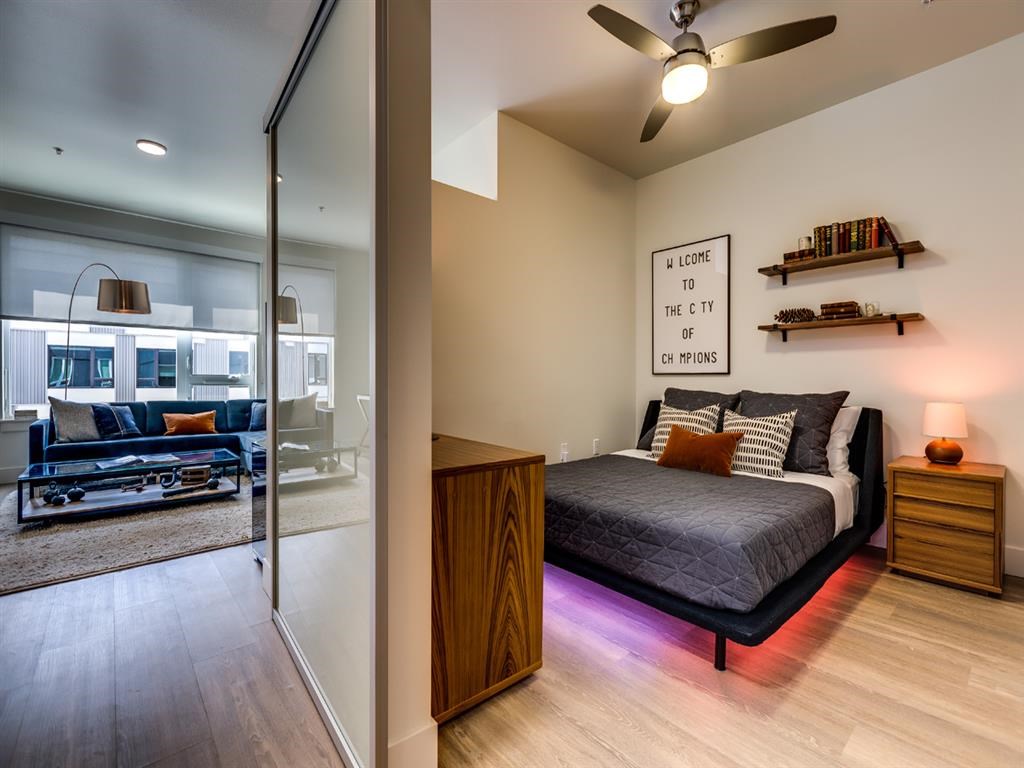a bedroom with a bed and a sliding glass door to a living room