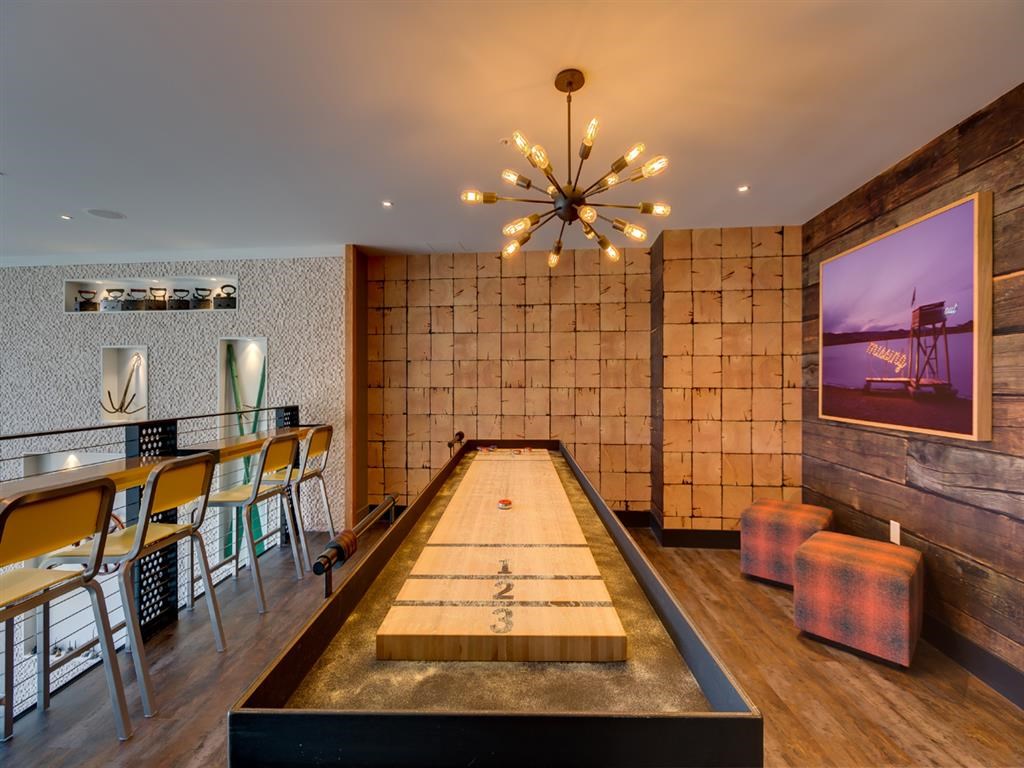 a long pool table in a room with a bar and chairs